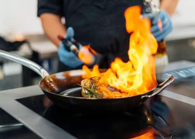 Chef-kok met handschoenen flambeing schotel