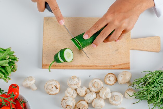 Chef-kok scherpe komkommer op houten raad in keuken in eenvormig vooraanzicht.