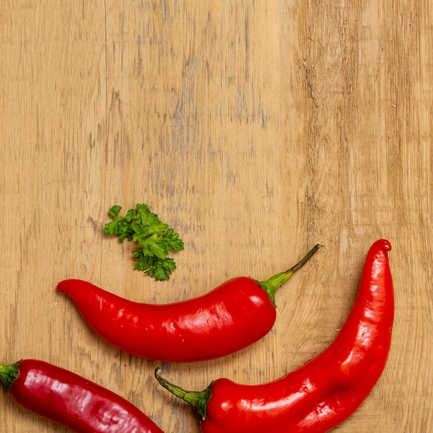 Gratis foto chili peppers en peterselie op houten tafel