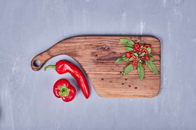 Chilipepers en kruiden op een houten bord.