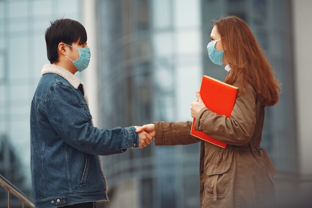 Chinese man en een vrouw in wegwerpmaskers schudden handen