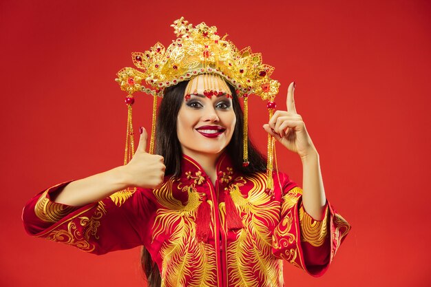 Chinese traditionele bevallige vrouw bij studio over rode achtergrond.