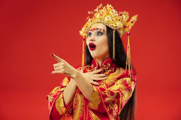 Chinese traditionele bevallige vrouw bij studio over rode achtergrond.