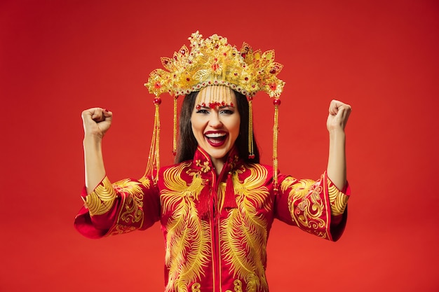 Gratis foto chinese traditionele bevallige vrouw bij studio over rode muur