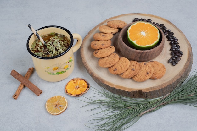 Gratis foto chip cookies en plakje mandarijn op een houten bord met kopje thee. hoge kwaliteit foto