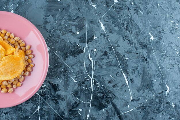 Chips en kikkererwten op een bord, op de blauwe tafel.