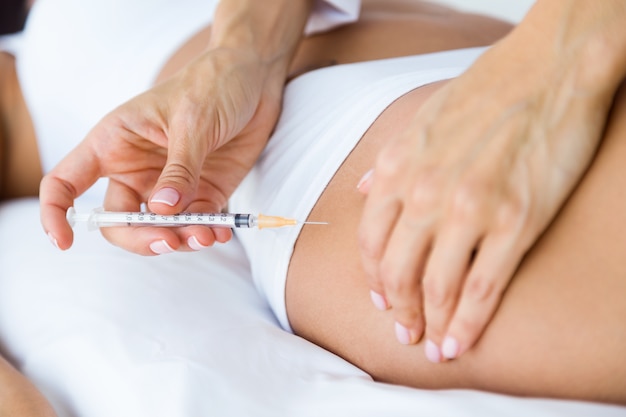 Chirurg die injectie in vrouwelijk lichaam maakt. Liposuctieconcept.