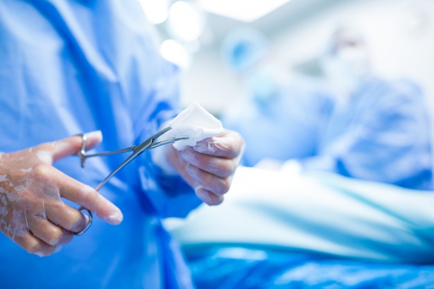 Chirurg snijden katoen uit schaar in verrichtingsruimte