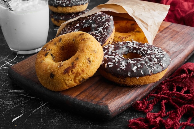 Chocolade donuts op een houten bord met gestremde melk.