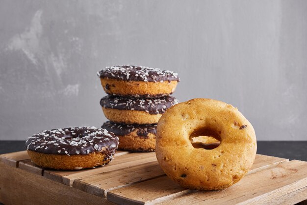 Chocolade donuts op een houten schotel.