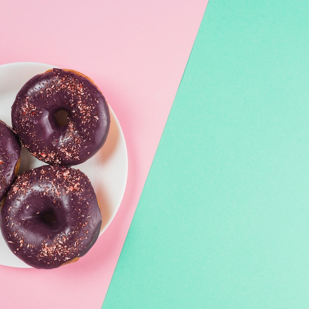 Gratis foto chocolade donuts op plaat op roze en muntachtergrond