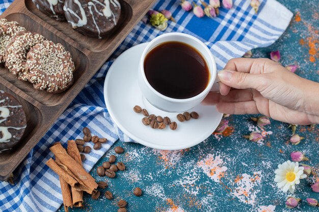 Chocolade- en kokoskoekjes op een houten bord geserveerd met een kopje thee.