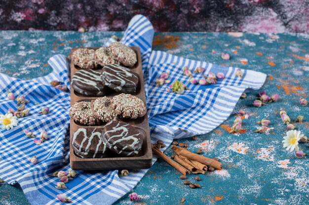 Chocolade- en kokoskoekjes op een houten bord geserveerd met een kopje thee.