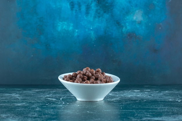 Chocolade maïs ballen in een kom, op de blauwe achtergrond. Hoge kwaliteit foto
