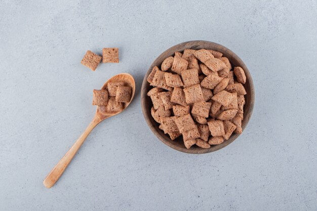 Chocolade pads cornflakes in houten kom op stenen oppervlak