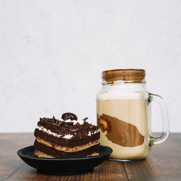 Chocolade smoothie in pot met een plakje cake op houten tafel