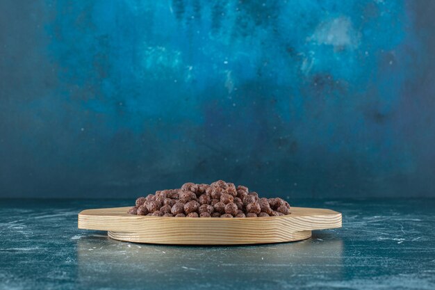 Chocolade suikermaïs ballen in een houten plaat, op de blauwe achtergrond. Hoge kwaliteit foto