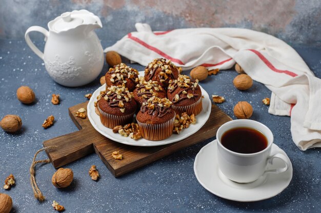 Chocolade-walnootmuffins met koffiekop met walnoten op donkere oppervlakte