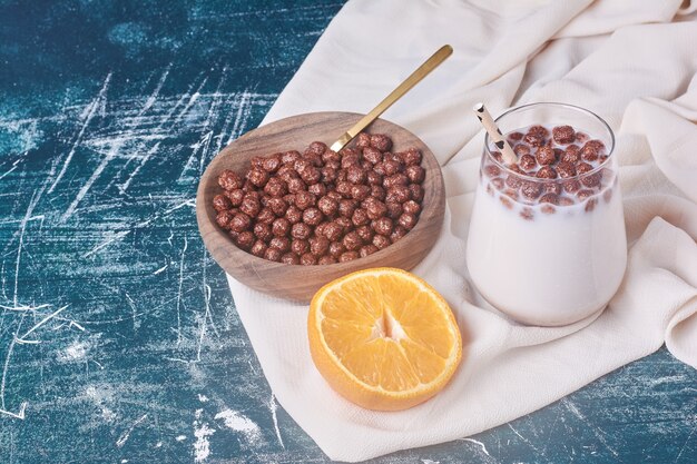 Chocoladebonen met een kopje melk op blauw.