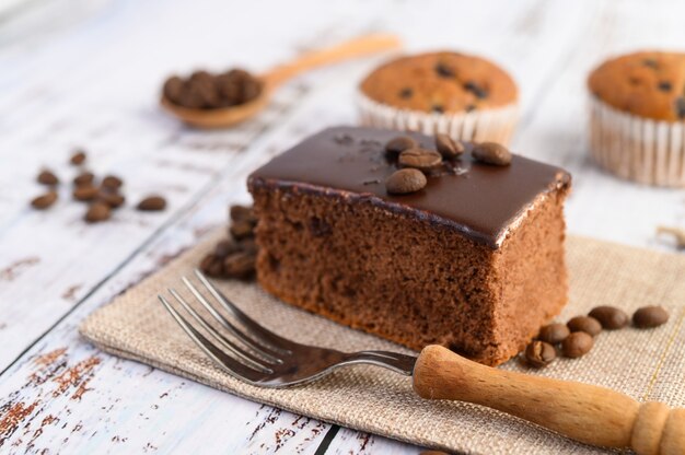 Chocoladecake op de zak en koffiebonen met vork op een houten lijst.
