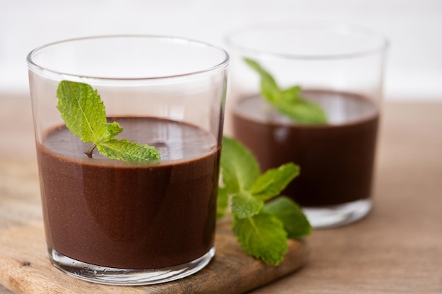 Gratis foto chocolademousse dessert gegarneerd met muntblad op houten tafel en witte achtergrond