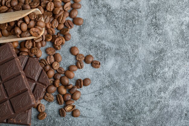 Chocoladerepen met koffiebonen op grijs.