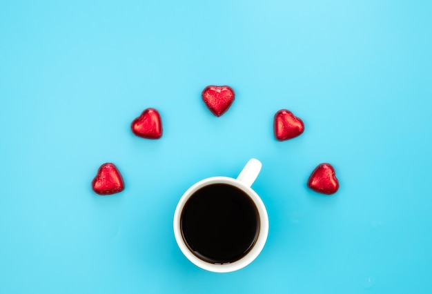Gratis foto chocoladesnoepjes in de vorm van harten en een kopje koffie op een blauwe achtergrond