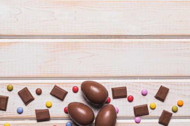 Chocoladestukjes; paaseieren en gem-snoepjes op de bodem van het houten bureau