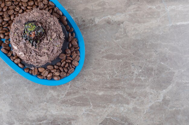 Chocoladetaart op een schaal vol koffiebonen op marmeren ondergrond