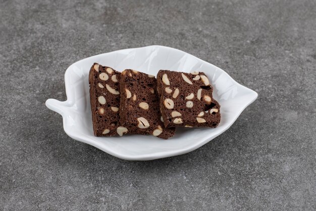 Chocoladetaartplakken op witte plaat over grijs oppervlak