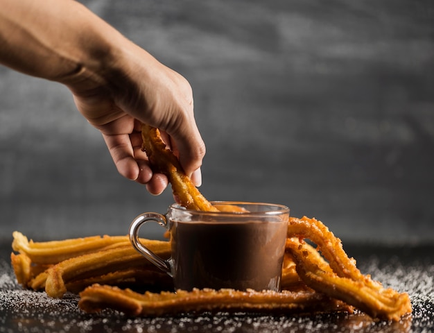 Churros dompelen in een beker gevuld met gesmolten chocolade