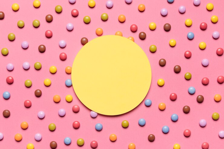 Gratis Foto cirkel geel kader over het kleurrijke multicolored gemsuikergoed op roze achtergrond