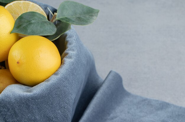 Gratis foto citroenen in een emmer bedekt met een stuk stof op marmer