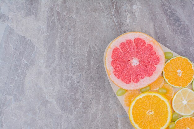 Citrusvruchten plakjes en druiven op een houten bord.