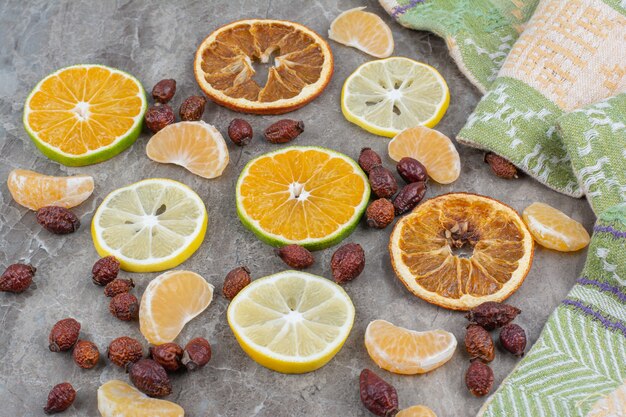 Citrusvruchtenplakken met rozebottels op steenoppervlak.