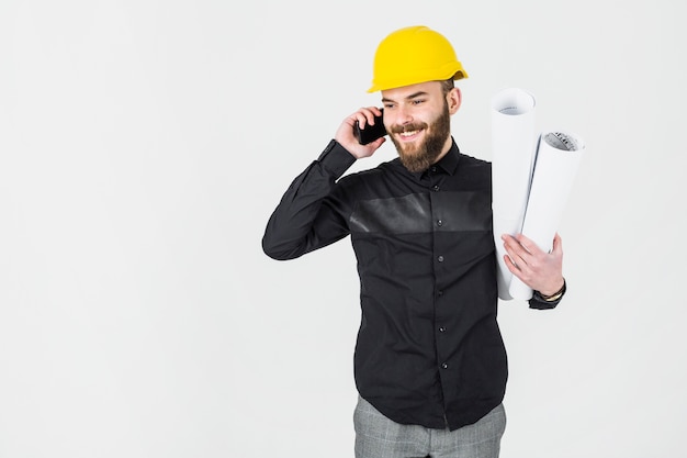 Civiel ingenieur met blauwdruk in zijn hand praten op mobiele telefoon