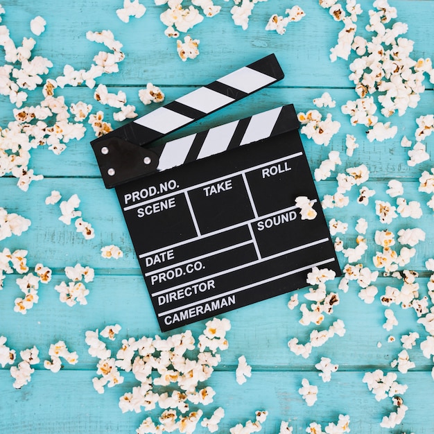 Gratis foto clapperboard op hoop gemorste popcorn