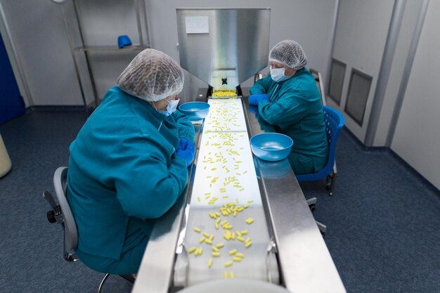 Cleanroom twee vrouwen in blauwe laboratoriumpakken werken online met pillen