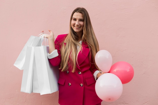 Cliënt die modekleding draagt en ballonnen middelgroot schot houdt