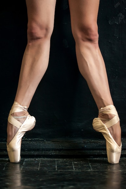 Close-up ballerina's benen en pointes op de zwarte houten vloer