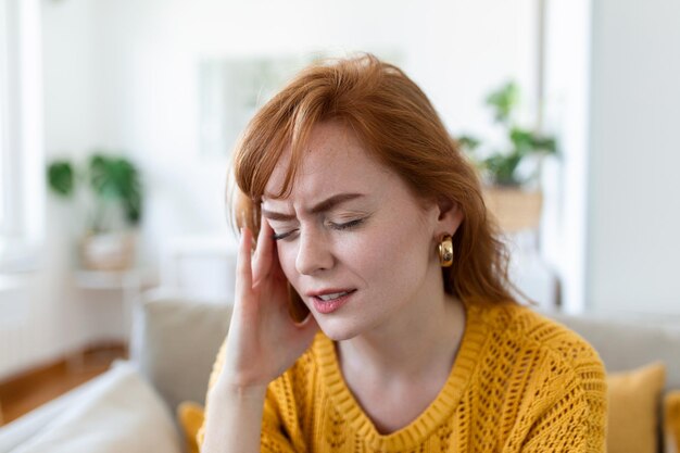 Close-up beeld frons gezicht van vrouw die sterke hoofdpijn voelt, tempel aanraakt om ernstige pijn te verminderen die lijdt aan paniekaanval op kantoor migraine overwerkte persoon of kater alcoholmisbruik concept