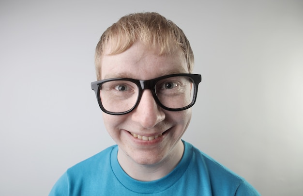 Close-up beeld van een blanke man die een blauw t-shirt en een bril draagt en grappige gezichtsgebaren maakt