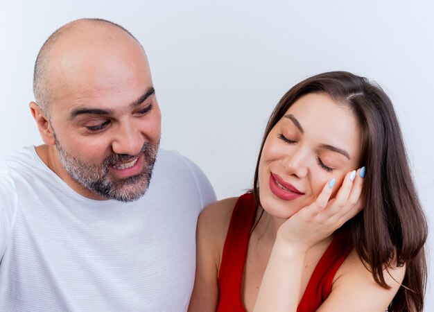 Close-up beeld van volwassen tevreden paar man kijken naar vrouw en vrouw hand op gezicht zetten met gesloten ogen