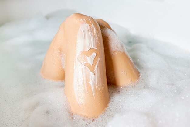 Close-up benen in badkuip met schuim