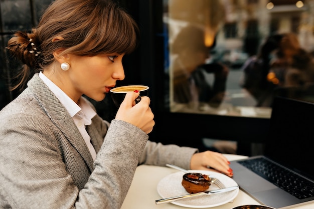 Close-up buiten portret van zakelijke vrouw gekleed jasje en blouse met een koffiepauze tijdens het werk hoge kwaliteit foto