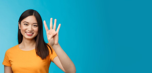 Gratis foto close-up charismatische tedere stijlvolle aziatische vrouw toont nummer vier vingers die vrolijk glimlachen om orde te maken