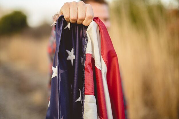 Close-up die van een mannetje is ontsproten dat de vlag van de Verenigde Staten houdt