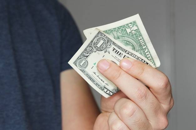 Close-up die van een persoon is ontsproten die een dollarbiljet van de VS op zijn hand houdt