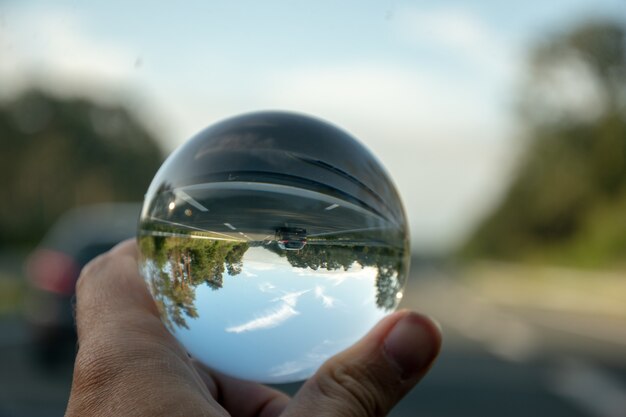 Close-up die van een persoon is ontsproten die een kristallen bol met de weerspiegeling van bomen houdt