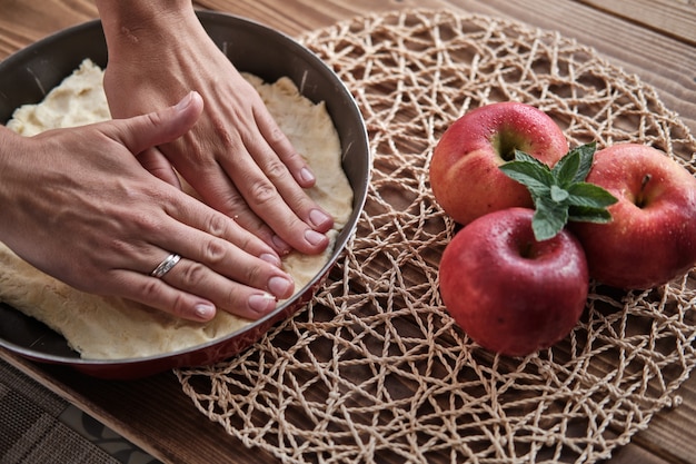 Close-up die van vrouwelijke handen is ontsproten die rode appeltaart voorbereiden